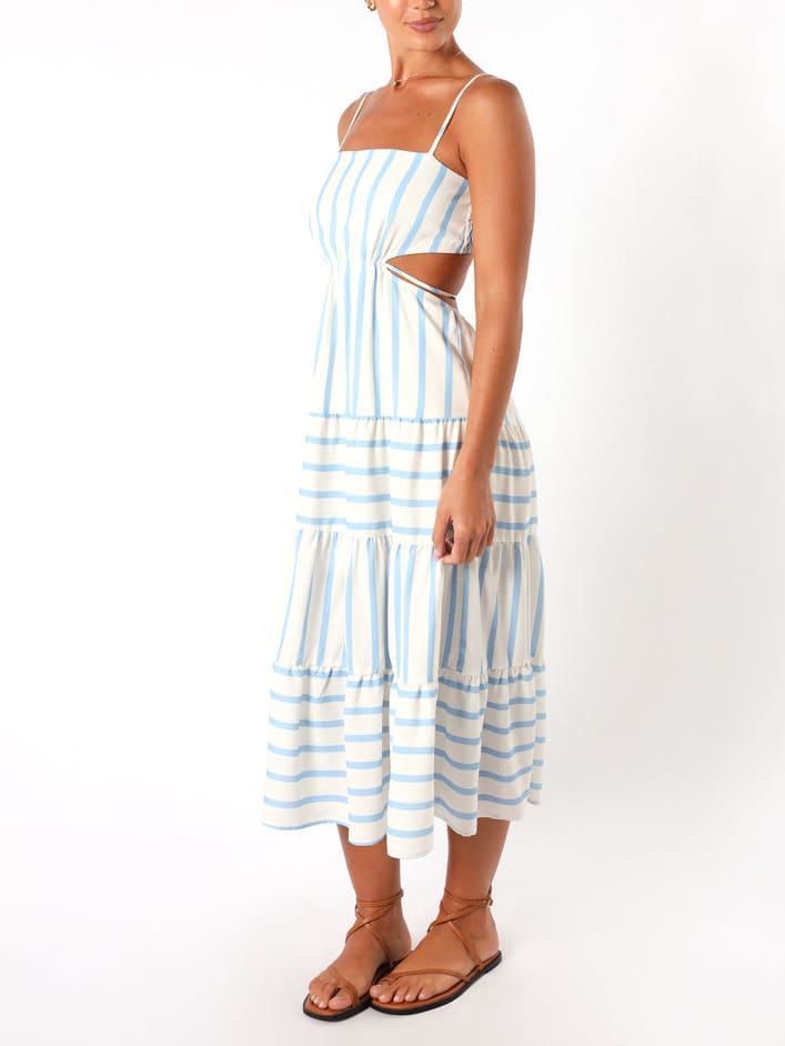 A woman wearing a light blue and white striped midi dress featuring a square neckline, thin spaghetti straps, side waist cutouts, and a tiered skirt with alternating stripe directions.