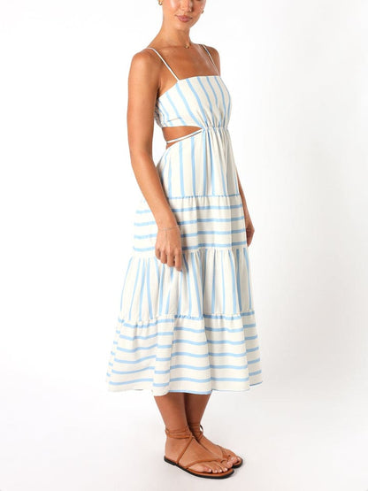 A woman wearing a light blue and white striped midi dress featuring a square neckline, thin spaghetti straps, side waist cutouts, and a tiered skirt with alternating stripe directions.