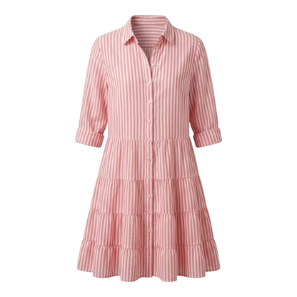 Green - A woman wearing a yellow and white vertical striped shirt dress with a collared neckline, button-down front, three-quarter sleeves, and a tiered skirt, standing on a sunlit cobblestone street.