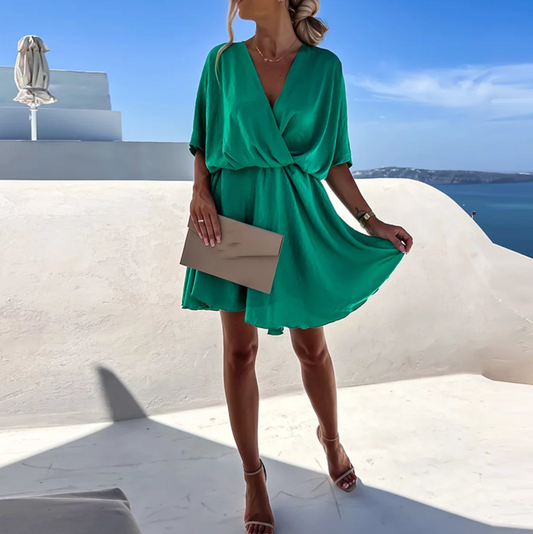 Green - Emerald green crepe mini dress featuring a draped surplice V-neckline, relaxed dolman sleeves, and a gathered A-line skirt.