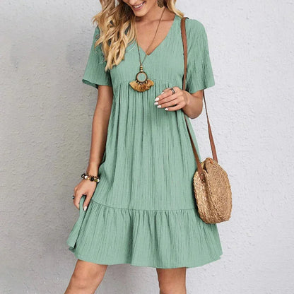 Light green textured crepe mini dress featuring a V-neckline, short sleeves, and a tiered babydoll silhouette.