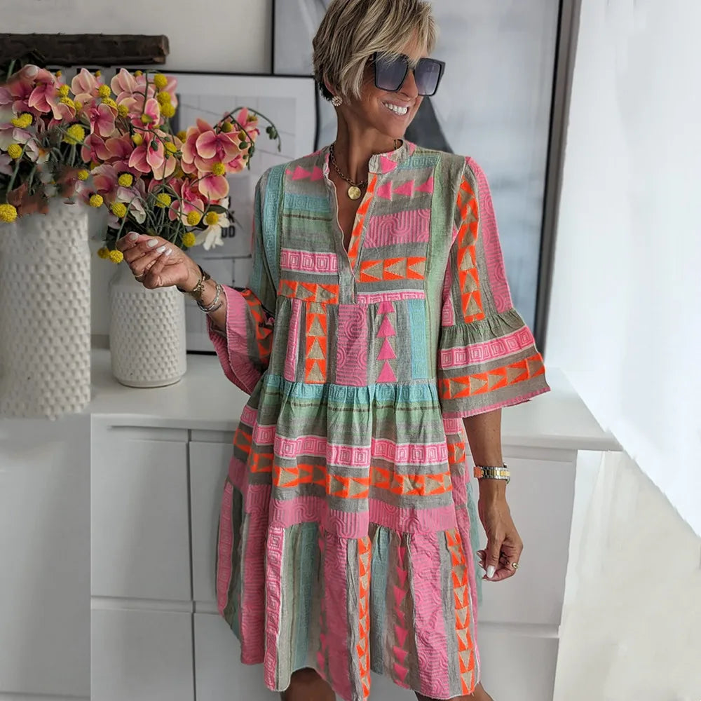 Light Green - A woman wearing a colorful, textured geometric print mini dress featuring a split neckline, three-quarter bell sleeves, and a tiered skirt.
