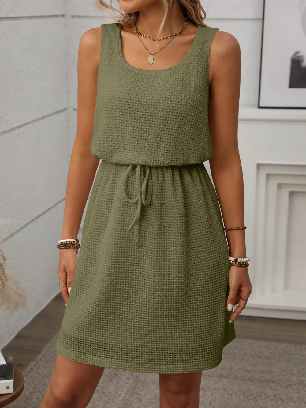 Green - Sleeveless textured knit mini dress featuring a scoop neckline and an adjustable drawstring waist.