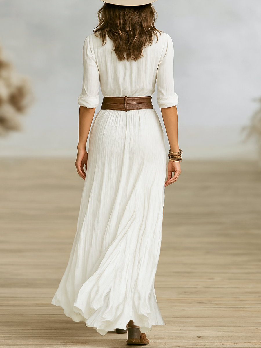 White - A woman wearing a white crinkled-texture maxi shirt dress with a ruched bodice, button-down front, and high leg slit, styled with a brown leather belt, cowboy boots, and a beige fedora hat.