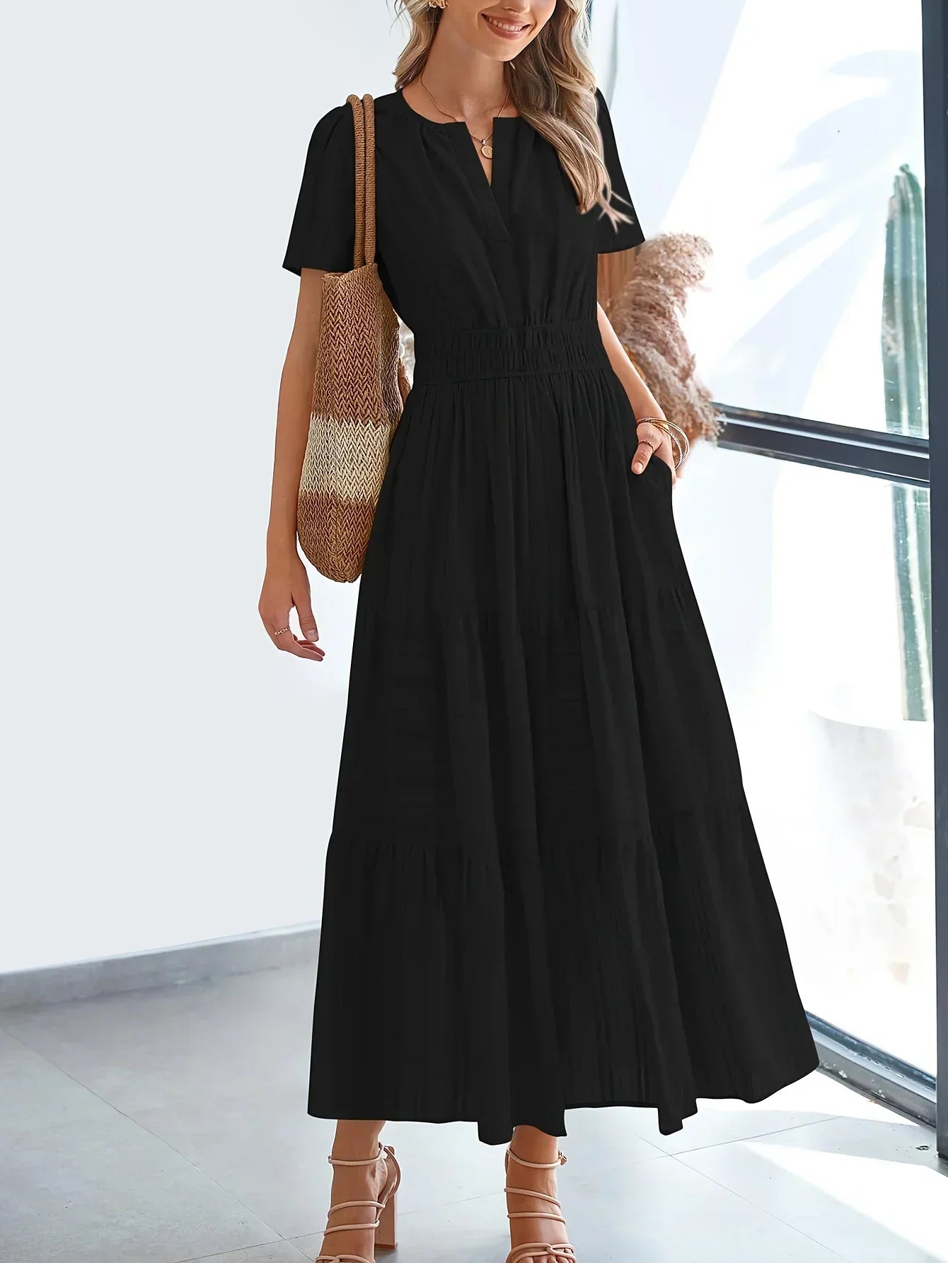 Black - A woman wearing a dusty pink, textured stripe maxi dress featuring a smocked waist, tiered skirt, short sleeves, and a split neckline, styled with a woven straw shoulder bag.
