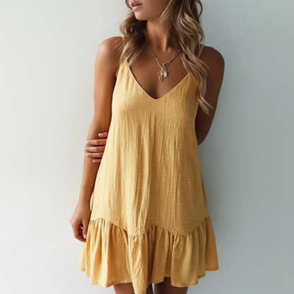 Green - A woman wearing a sleeveless, mustard-yellow mini dress with a textured crinkle fabric, V-neckline, thin spaghetti straps, and a ruffled hem.