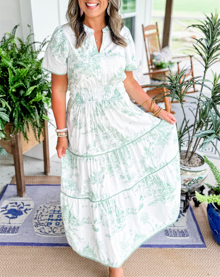 Green - A woman wearing a white tiered maxi dress with a brown toile de Jouy print, featuring short puff sleeves, a smocked waist, and a split neckline.
