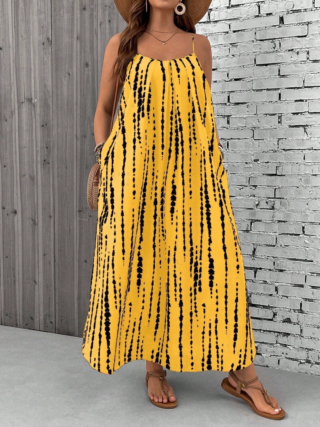 Yellow - A woman stands on a sandy beach wearing a sleeveless maxi dress with a bold green, pink, and yellow tropical leaf print, featuring spaghetti straps and side pockets.